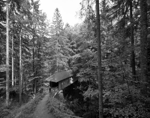 eine Holzbrücke mit Ziegeldach in einer Schlucht in Dornbirn Gütle